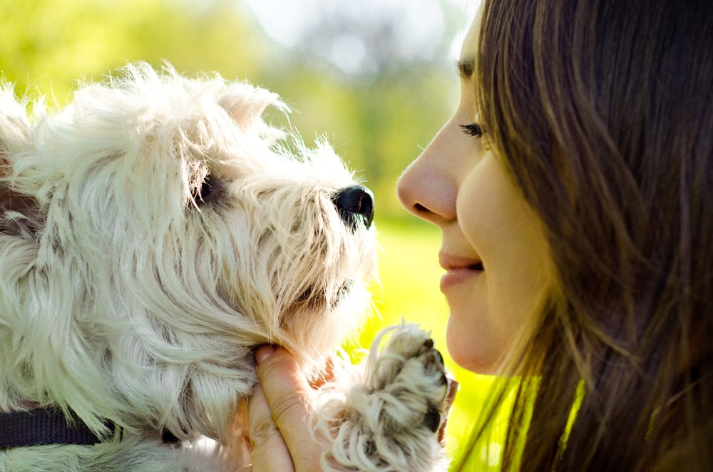 Eine Frau hält einen kleinen weißen Hund im Freien.